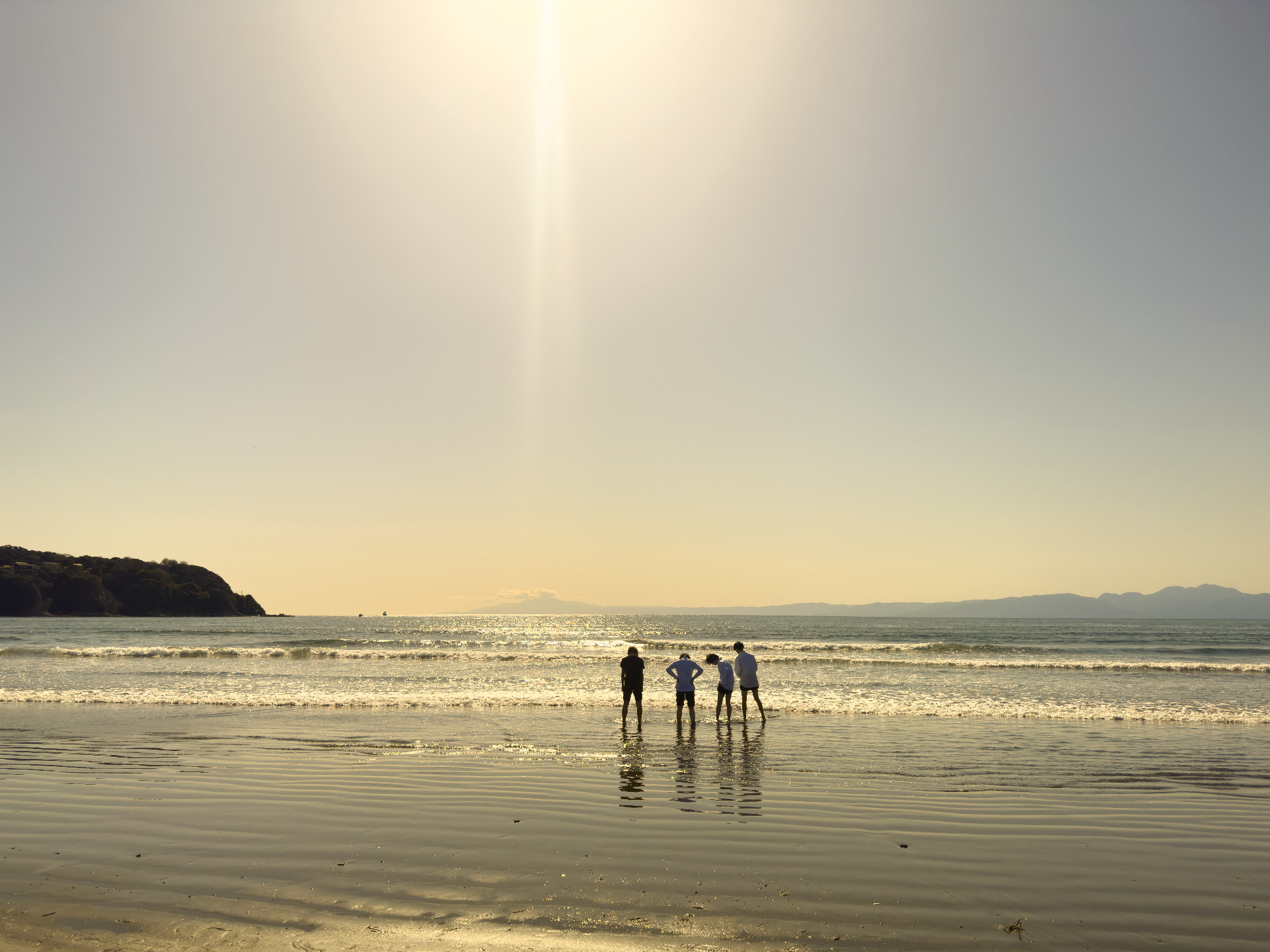 Menschen am Strand bei tief stehender Sonne